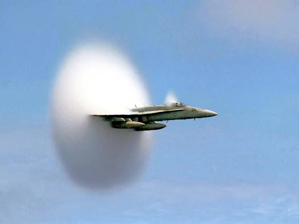 Avión de combate F/A-18 envuelto en un cono de vapor de agua al volar cerca de la velocidad del sonido sobre el mar