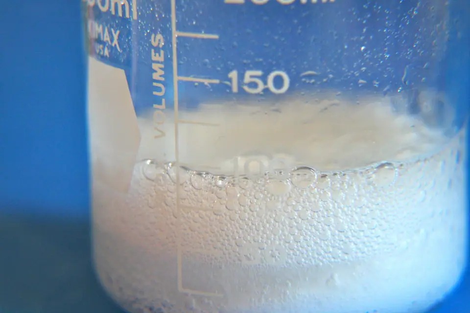 Vaso de precipitados con espuma blanca de bicarbonato y vinagre