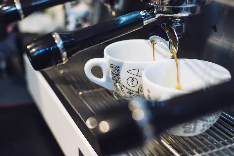 Máquina de espresso sirviendo café en dos tazas blancas