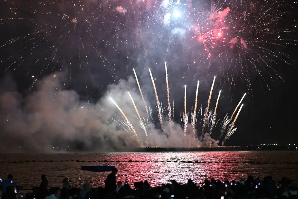 Fuegos artificiales de distintos colores estallando sobre el agua durante un espectáculo nocturno