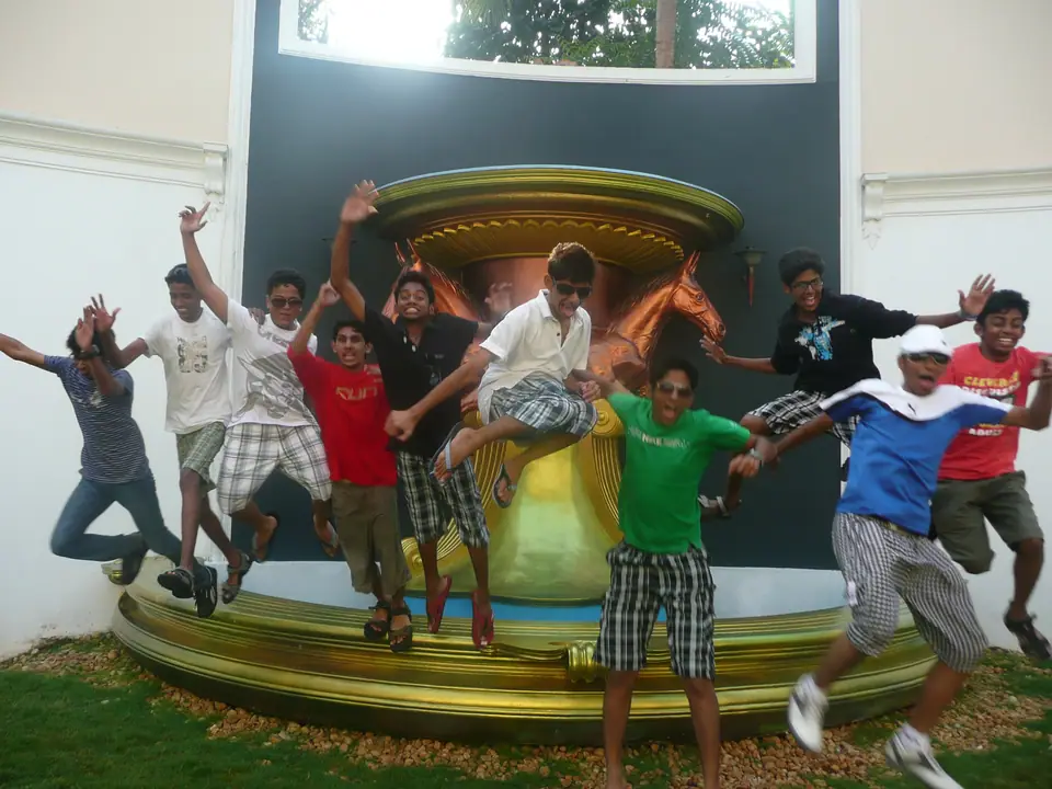 Un grupo de jóvenes salta al mismo tiempo frente a una escultura dorada; todos están en el aire