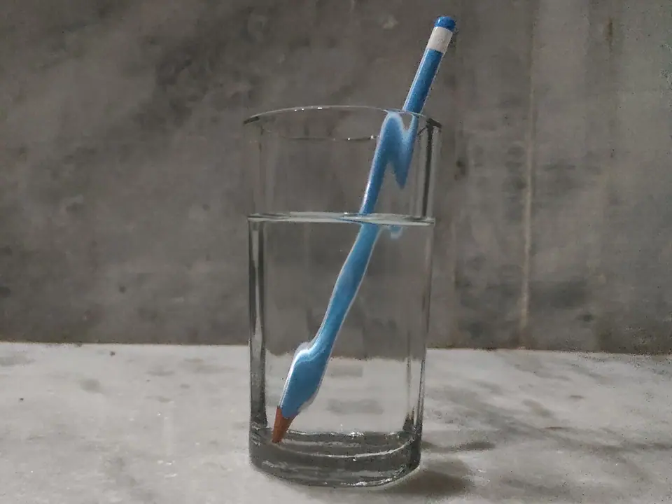 Lápiz azul dentro de un vaso con agua: la parte sumergida aparece desplazada y parece quebrada en la superficie