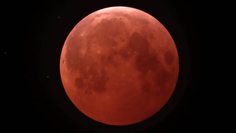 La Luna llena teñida de rojo cobrizo durante la totalidad de un eclipse lunar, sobre el cielo negro