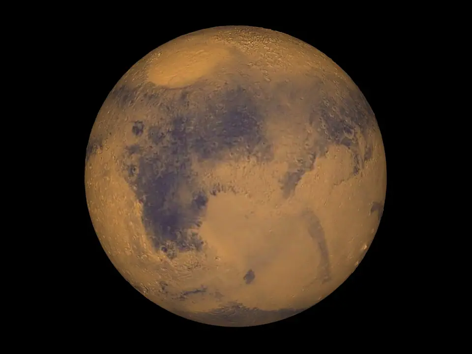 Marte visto desde el espacio: un disco ocre anaranjado con manchas oscuras y el casquete polar