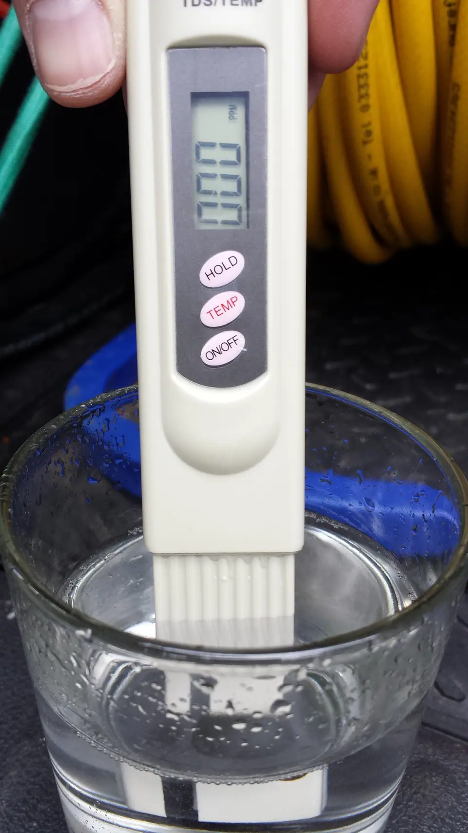 Medidor digital de sólidos disueltos (TDS) sumergido en un vaso de agua, el instrumento que mide cuántos iones lleva disueltos el agua y qué tanto puede conducir electricidad