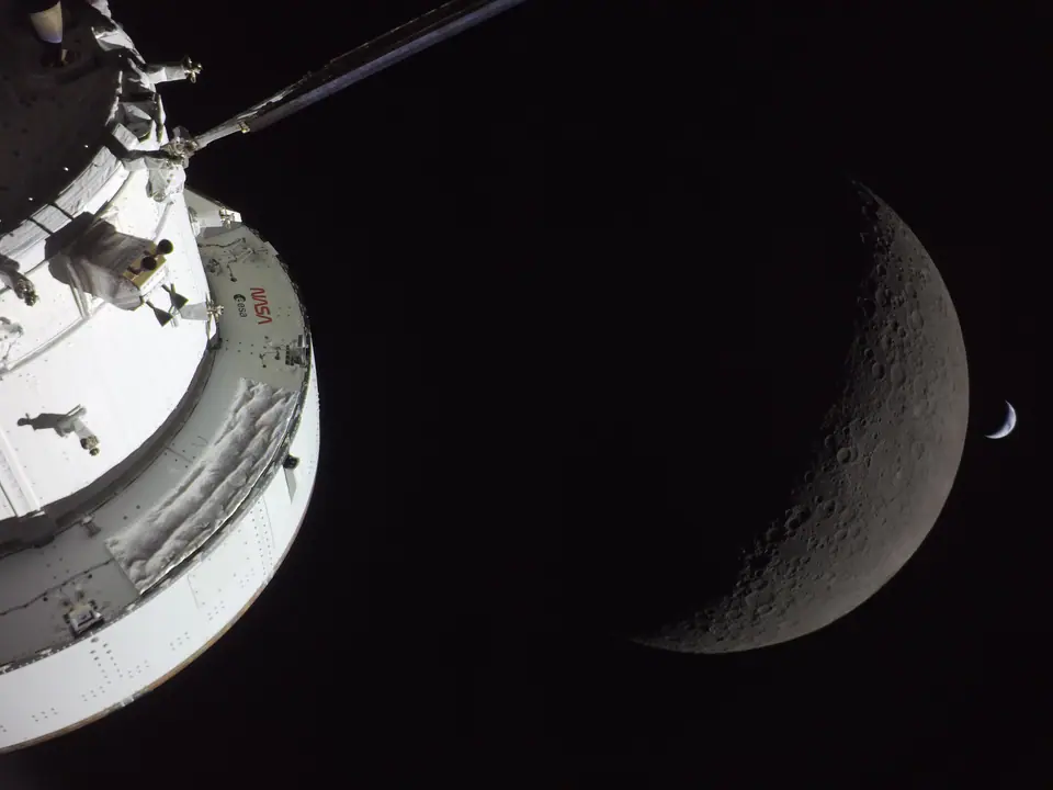 La nave Orion de la misión Artemis I en primer plano, con la Luna en fase creciente al fondo durante su viaje de 2022