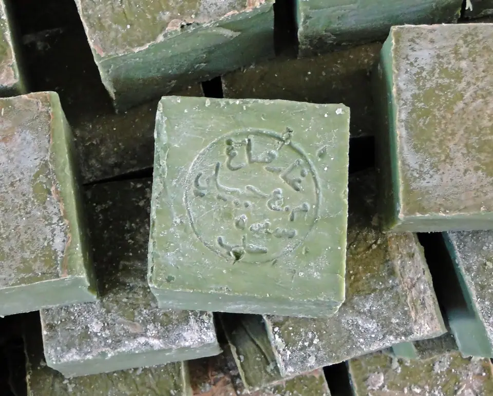 Panes de jabón de Alepo apilados, verdes por fuera, con un sello grabado en la cara de arriba
