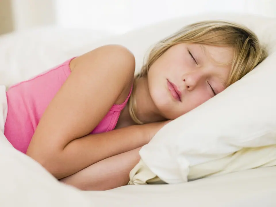 Persona dormida de costado sobre una almohada blanca