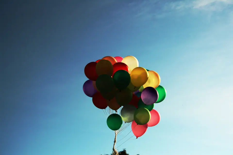 Racimo de globos de colores inflados con helio contra el cielo azul