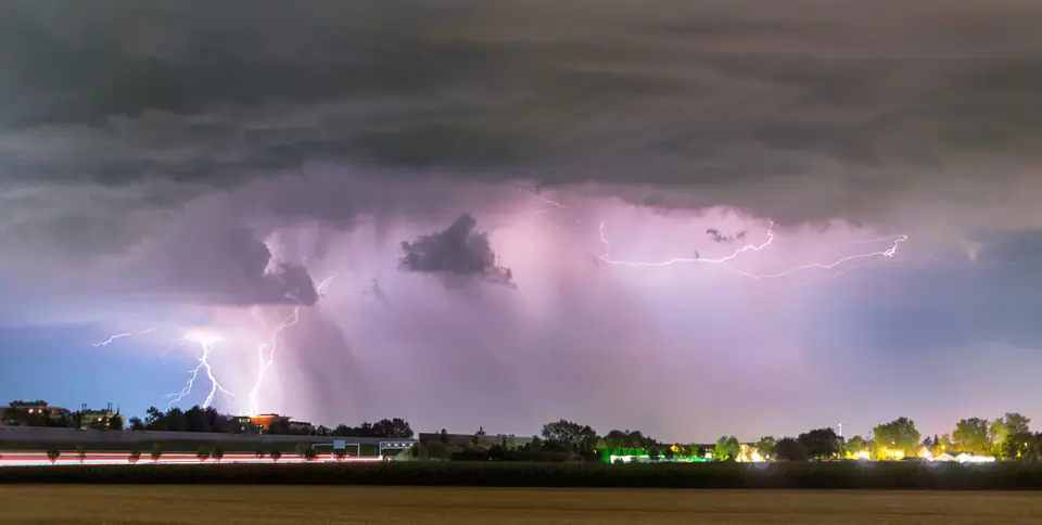 Tormenta lejana de noche sobre una llanura: la nube se ilumina por dentro con relámpagos y algunos rayos bajan al horizonte