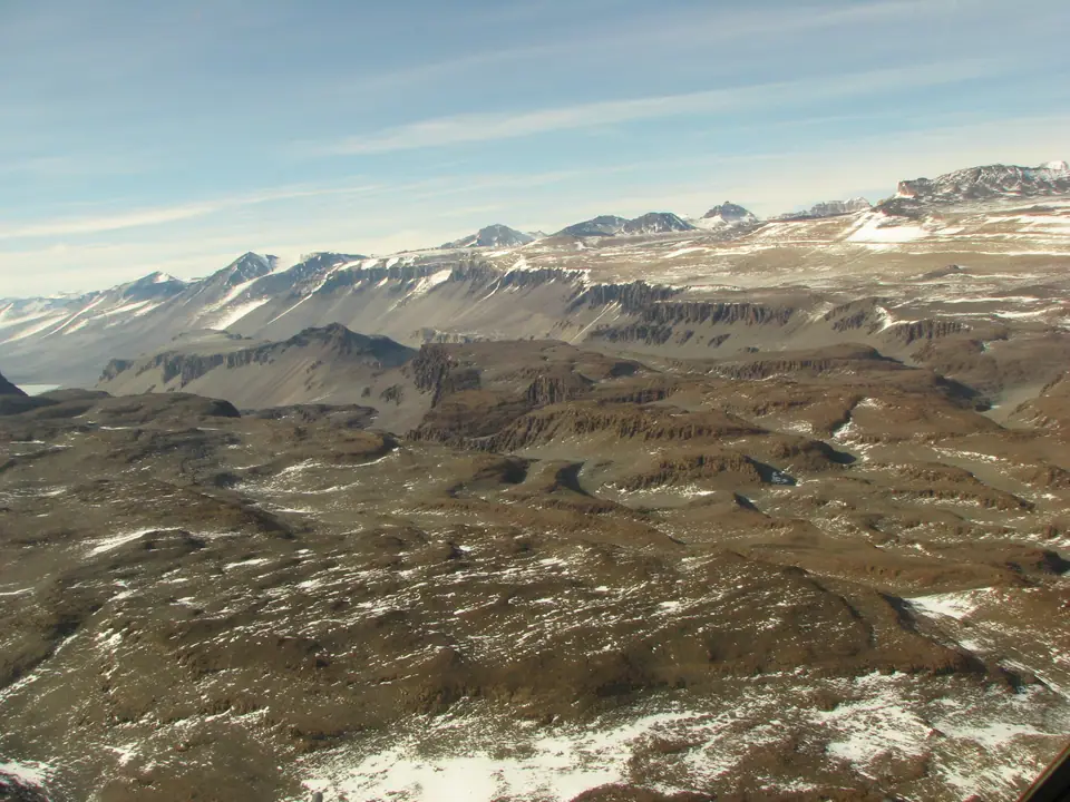 Vista aérea de los valles secos de McMurdo, en la Antártida, con suelo rocoso sin hielo y glaciares al fondo